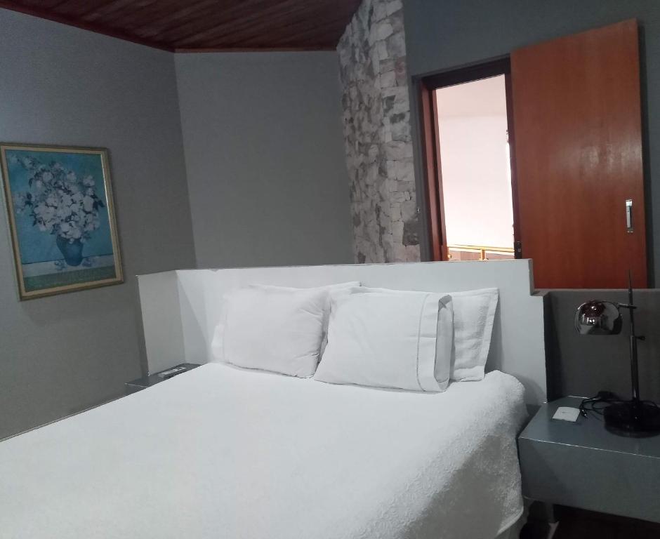a bedroom with a bed with white sheets and pillows at CORTESE HOTEL in Tatuí