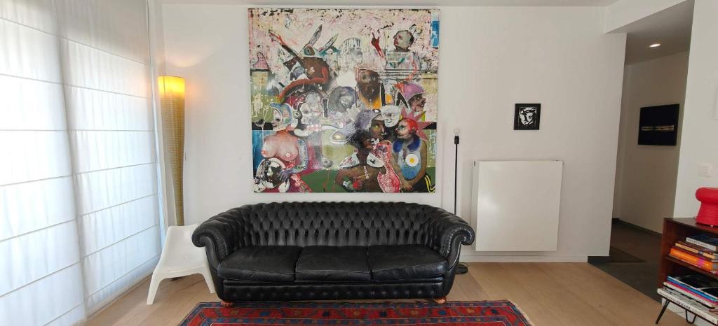 a black leather couch in a living room with a painting at Zeebrugge Sea View, Family-Friendly & the Beach! in Zeebrugge