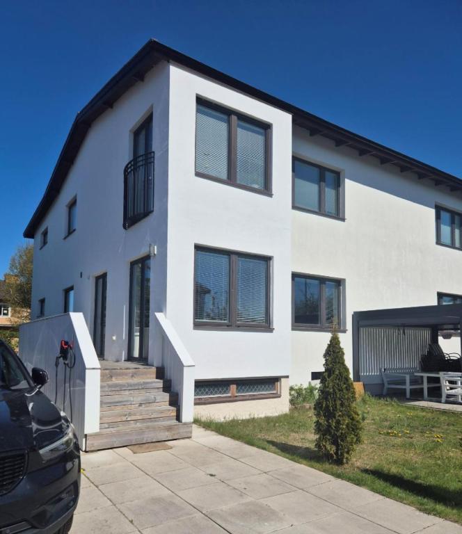 a white house with a car parked in front of it at Charmig bottenvåning i Limhamn in Limhamn