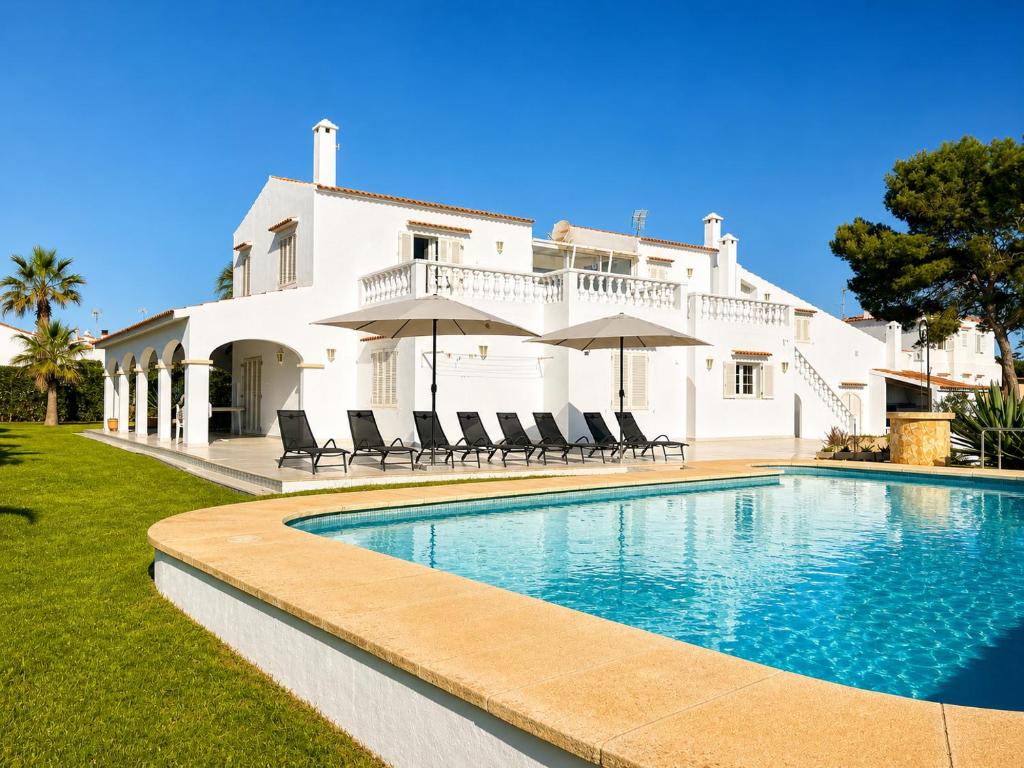 a villa with a swimming pool in front of a house at Villa Savanna Spacious villa with private pool near the beach in Cala en Blanes