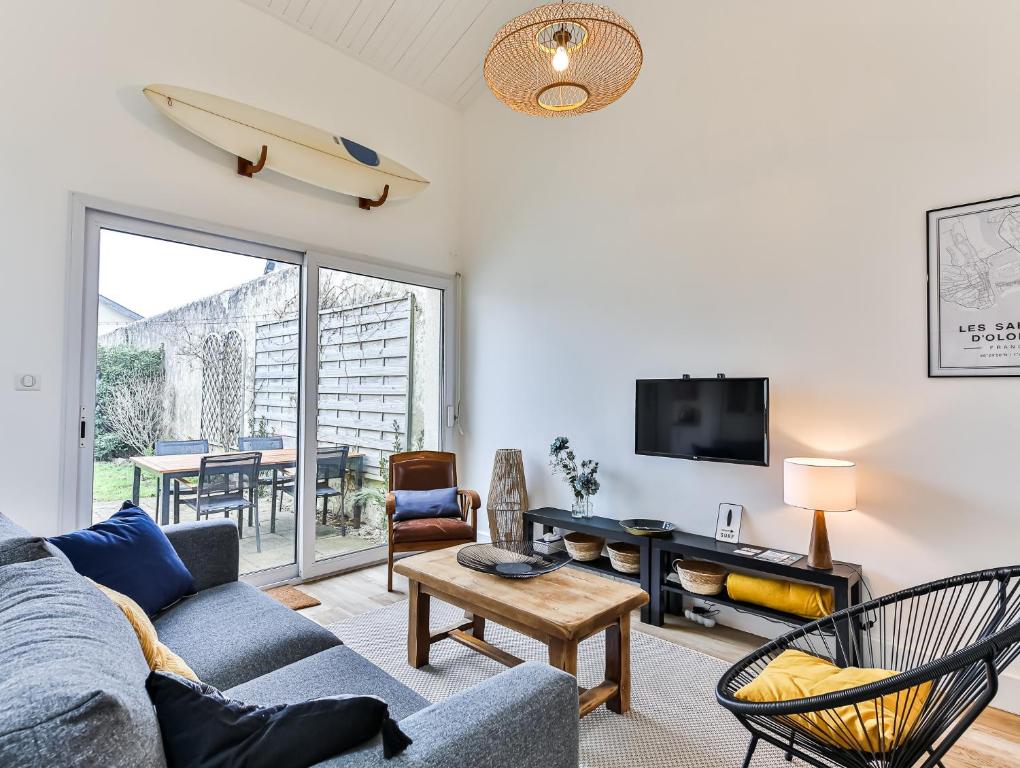 a living room with a couch and a table with a surfboard on the wall at Maison des Surfeurs in Les Sables-d'Olonne