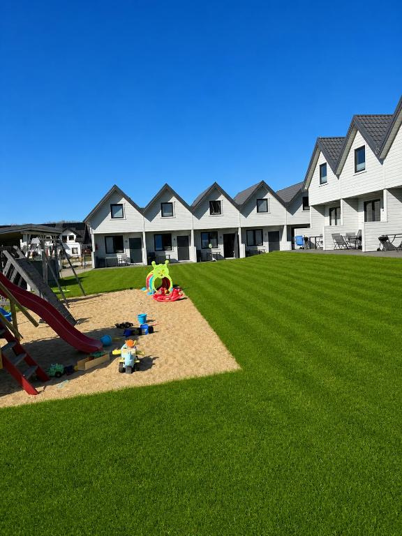a playground with a slide in a grass field at Domek Ga-Ba in Sarbinowo