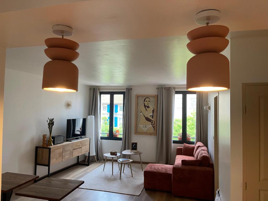 a living room with a red couch and two lights at La Clef de la Place in Leucate