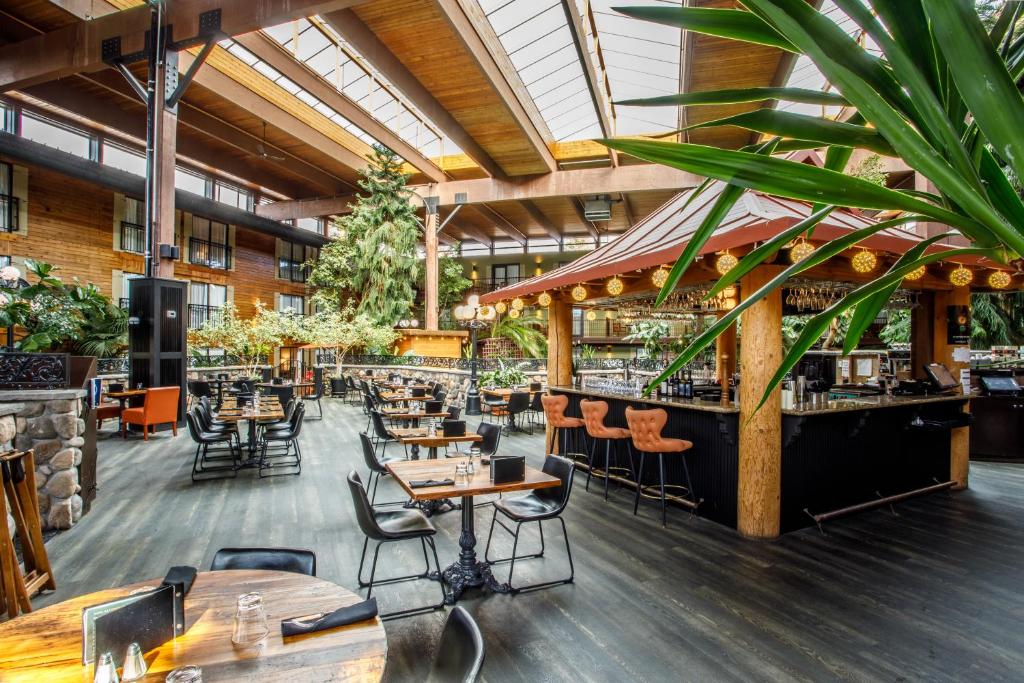 a restaurant with tables and chairs and a bar at Prestige Vernon Lodge in Vernon