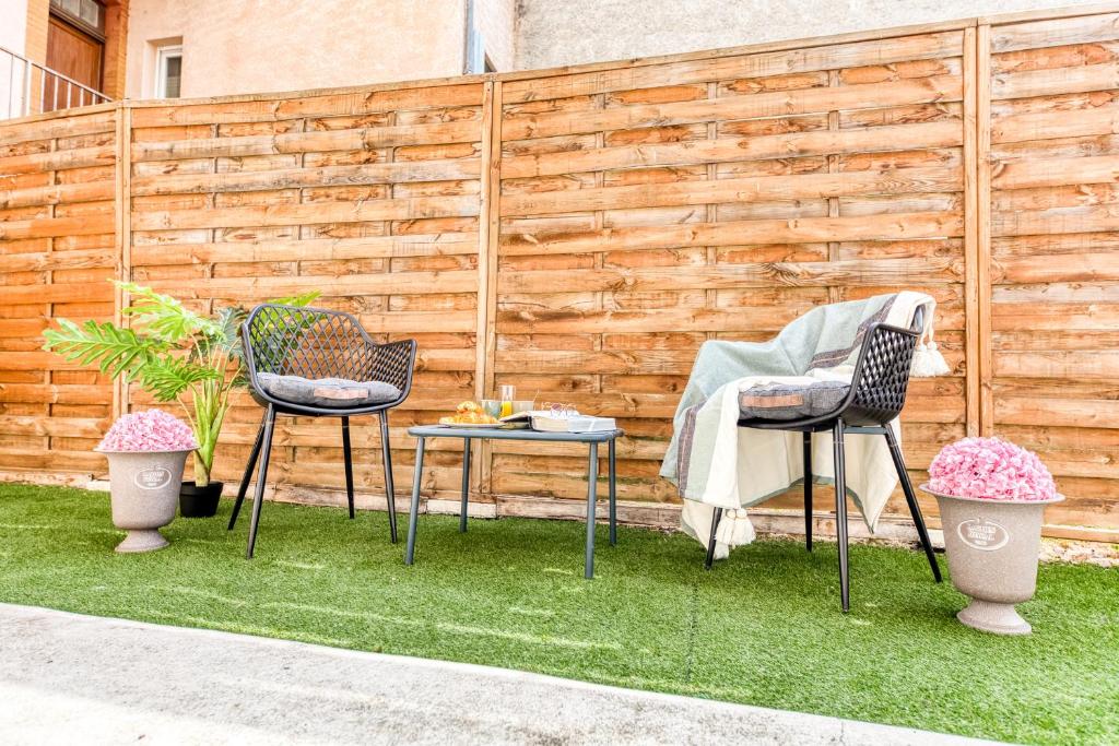 two chairs and a table in front of a fence at Cocon lumineux au centre de Tarbes, terrasse privée au soleil, confort tout inclus in Tarbes