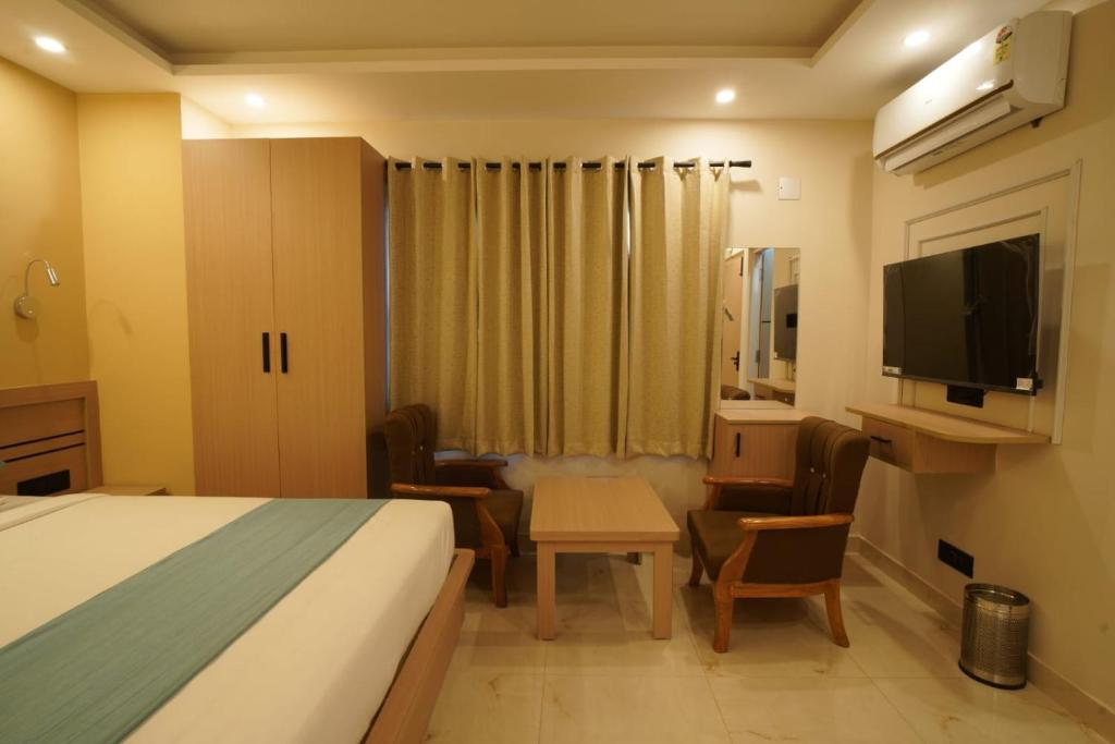 a hotel room with a bed and a desk and a television at Shree Goljyu Palace in Almora