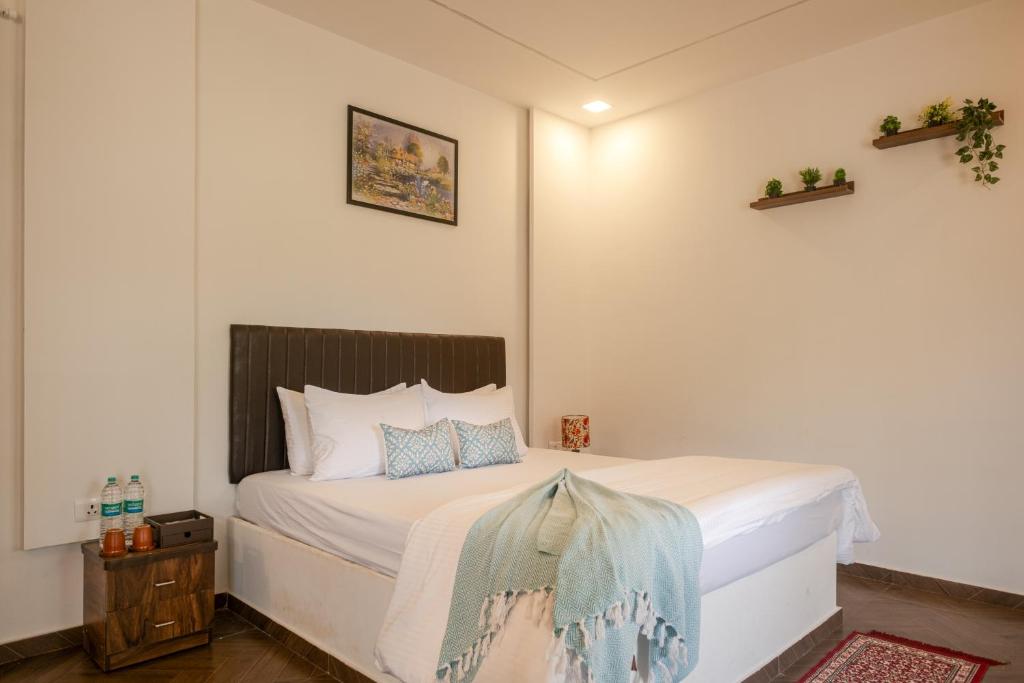 a bedroom with a bed with white sheets and blue pillows at Amra Woods in Karjat