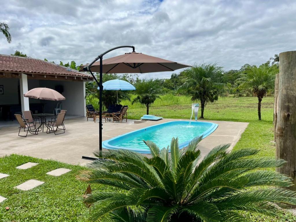 a pool with an umbrella and a table and chairs at Chácara com piscina, lazer e muita natureza in Morretes