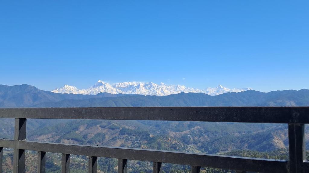 a wooden bench with mountains in the background at The himaliyan munros in Rānīkhet