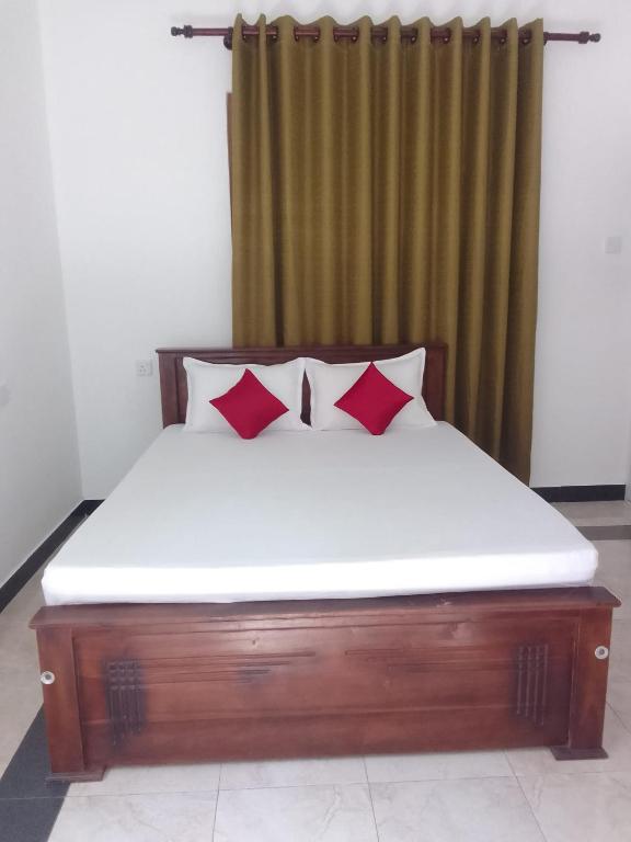 a bed with two red pillows in a room at Sette Stelle in Pahala Maragahawewa