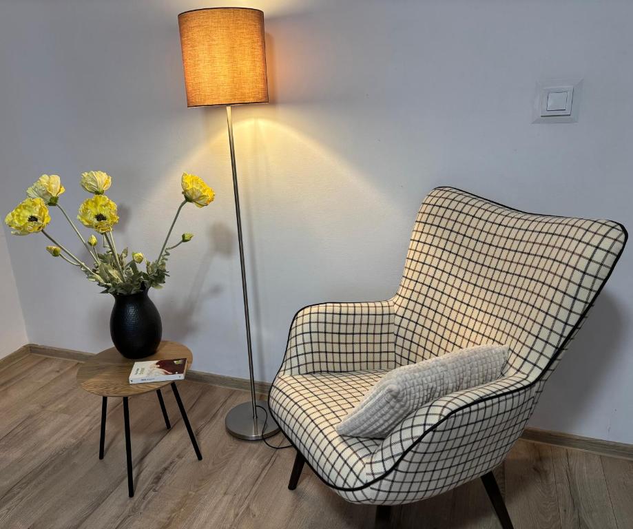 a chair and a lamp and a vase with yellow flowers at Sunny Apartment in Constanţa