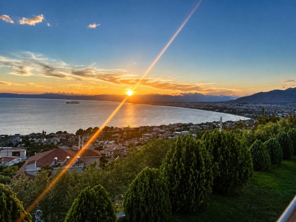 a view of a city with the sun setting over the water at Panorama View in Kalamata