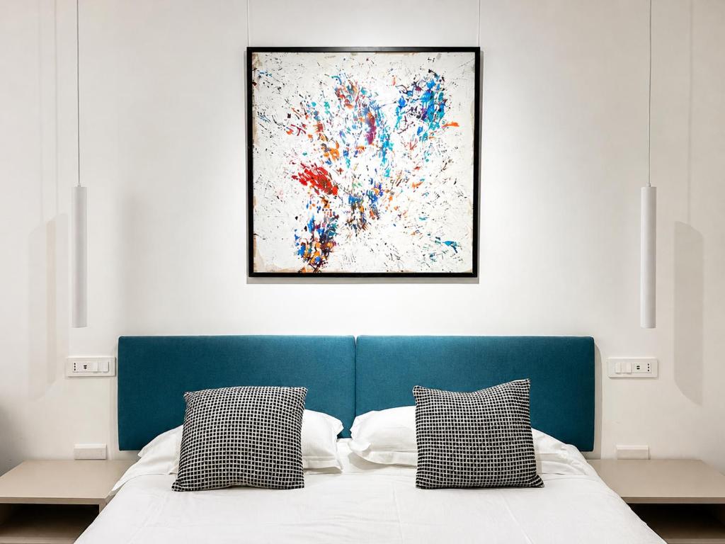 a bedroom with a blue bed with a painting on the wall at The Mamas in Oristano