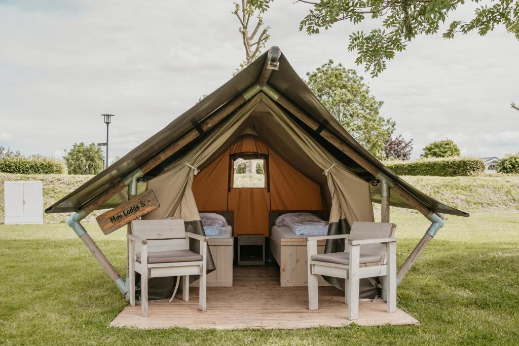 ein Zelt mit zwei Stühlen und einem Bett darin in der Unterkunft Safaritent Mini Lodge in Kesteren