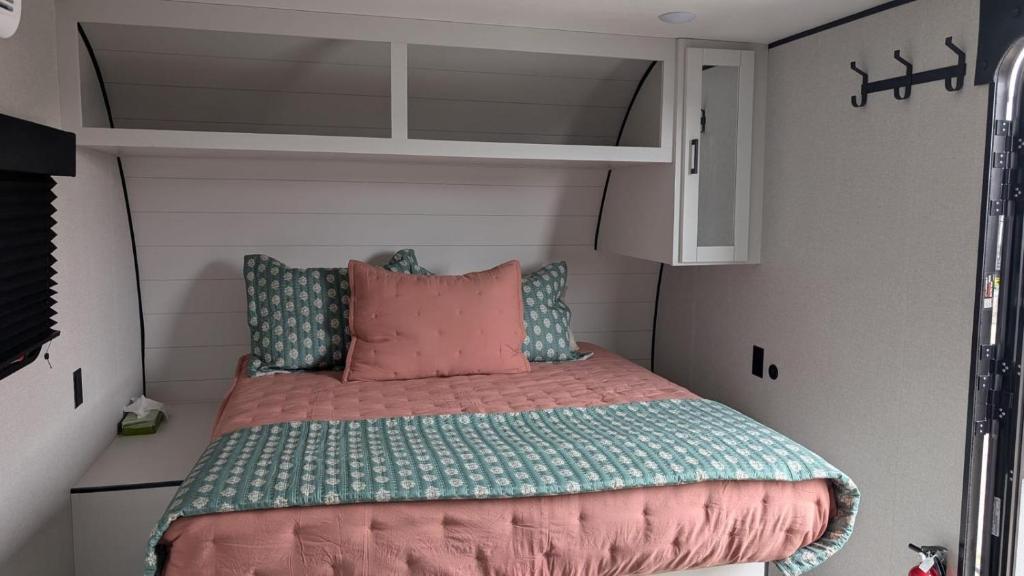 a bed in a small room with a shelf at Gtown Campers in Geraldton