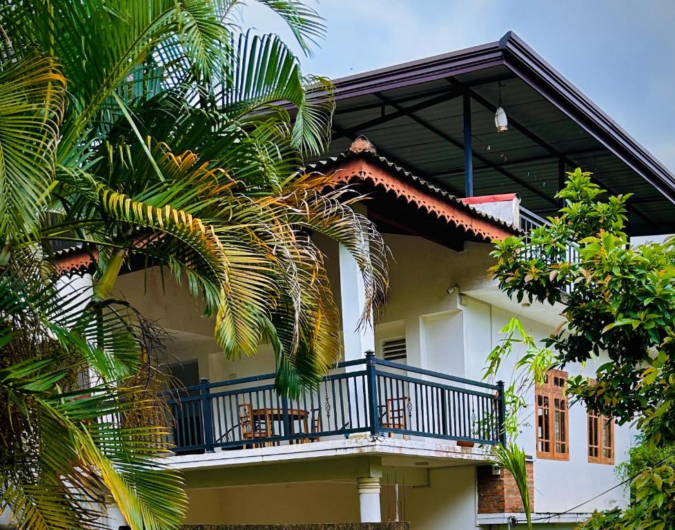 a white house with a balcony and palm trees at Goldern Gate in Kandy