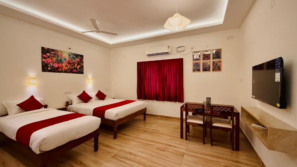 a hotel room with two beds and a flat screen tv at Ayaf Homes in Pondicherry
