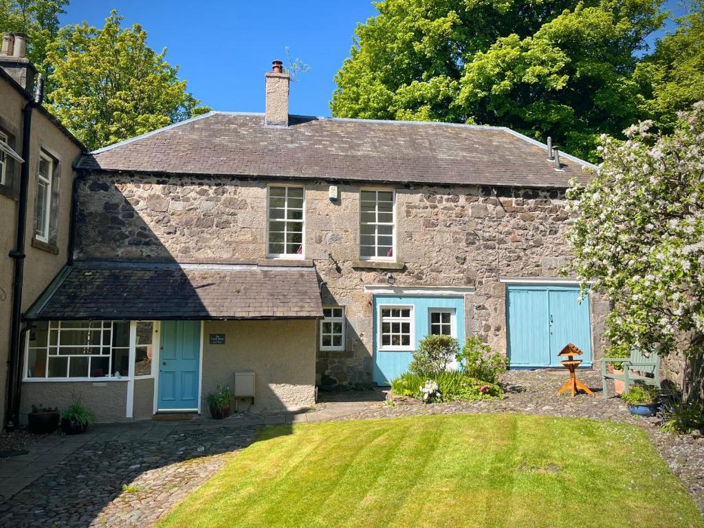 an old stone house with blue doors and a yard at The Coach House in Stirling