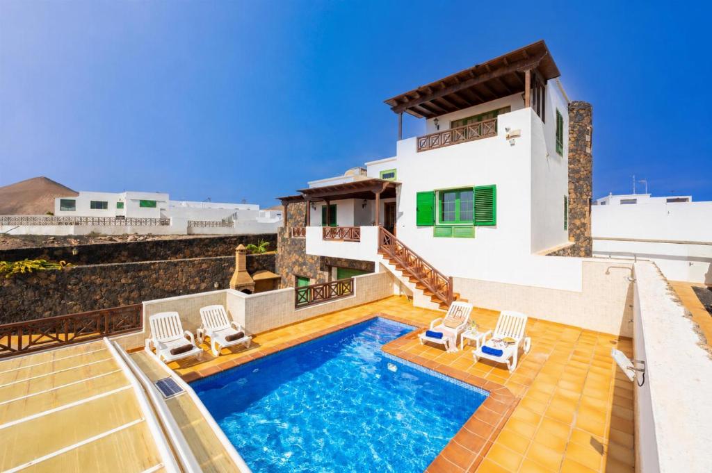 a villa with a swimming pool and chairs at Casa Morro Blanco in Conil