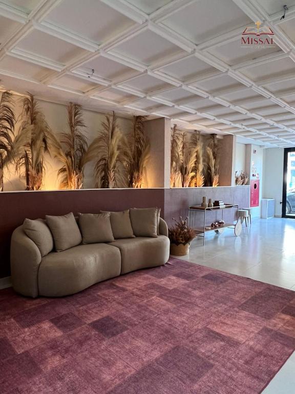 ein Wohnzimmer mit einer Couch und Palmen an der Wand in der Unterkunft Missal Hotel in Aparecida