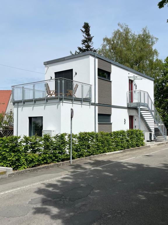a white house with a balcony on a street at Flying Spaces am Hechtweiherpark in Günzburg