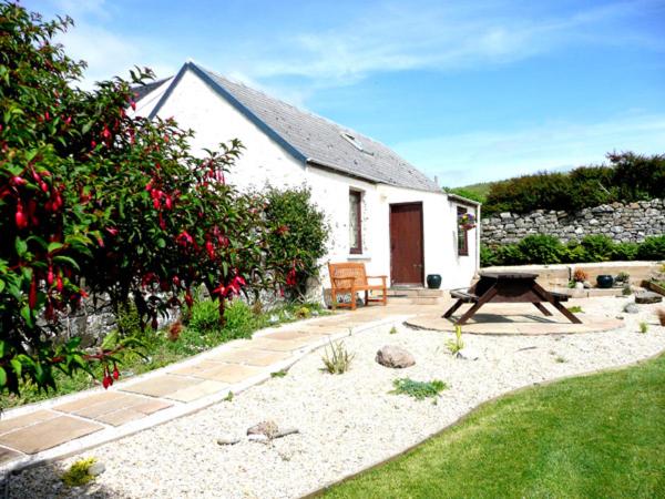 a house with a bench in front of a garden at Scoor - Garden Cottage in Bunessan