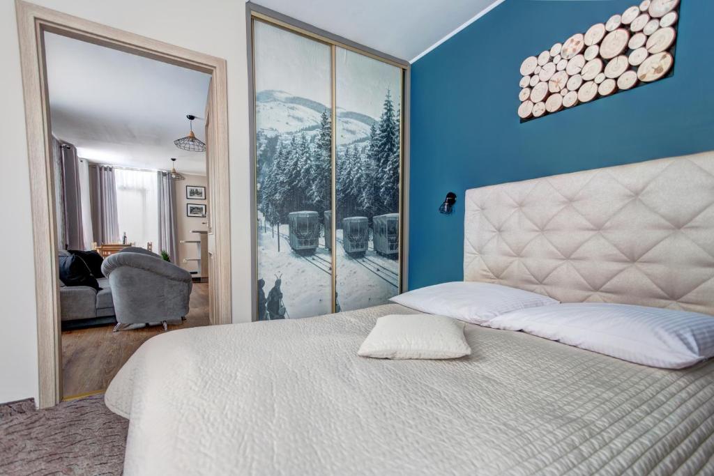 a bedroom with a white bed and a blue wall at Apartamenty Parkowa in Krynica Zdrój