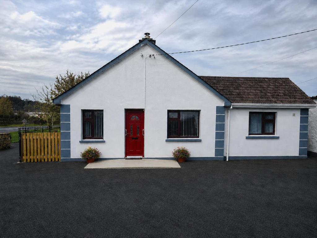 a white house with a red door at Katie's Cottage in Laghy