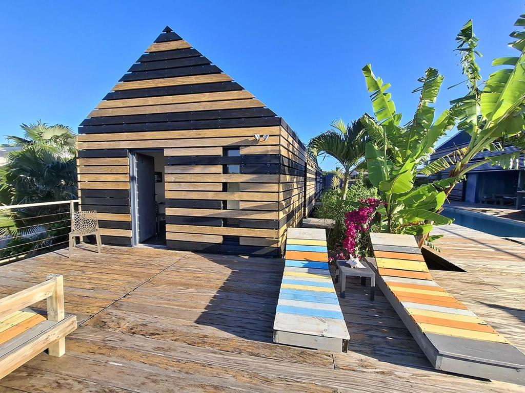 a small wooden house with benches on a deck at La Case des Caraïbes in Le Gosier