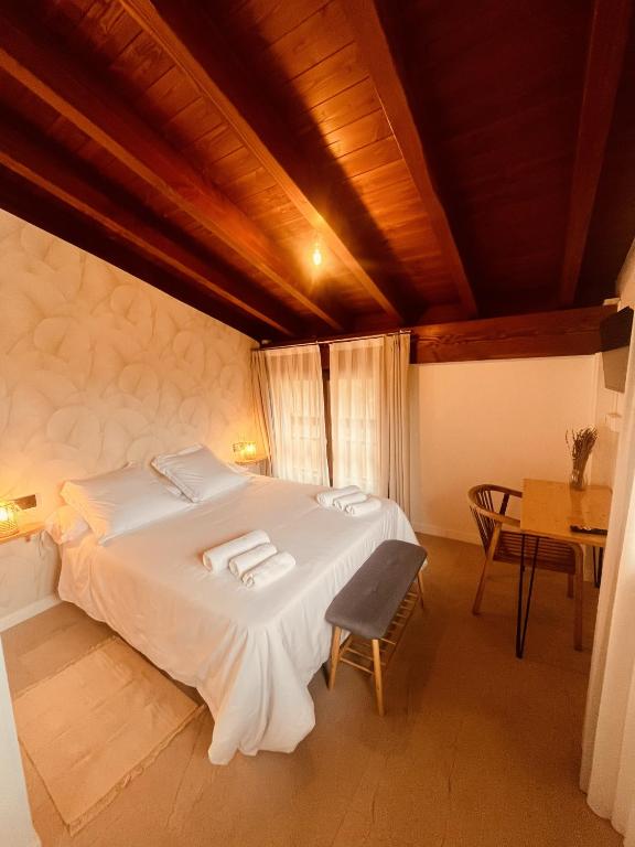 a bedroom with a large white bed and a table at Casa Kirana - Habitaciones in Bermeo