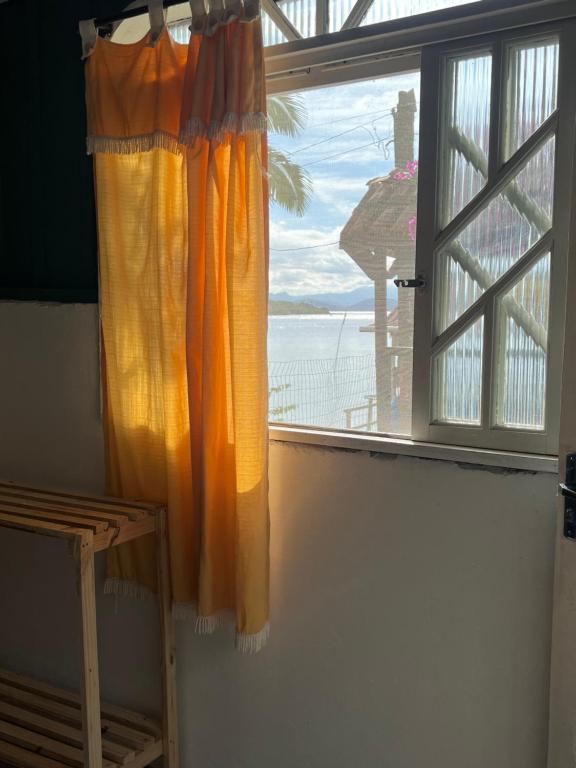 a window with an orange curtain in a room at Pousada ilha das gamelas in Guaraqueçaba