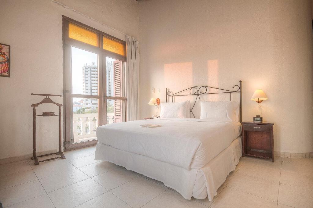 um quarto com uma grande cama branca e uma janela em Hotel Monterrey em Cartagena de Indias