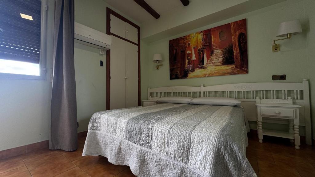 a bedroom with a bed and a painting on the wall at Hosteria Conchi in Madrigal de la Vera