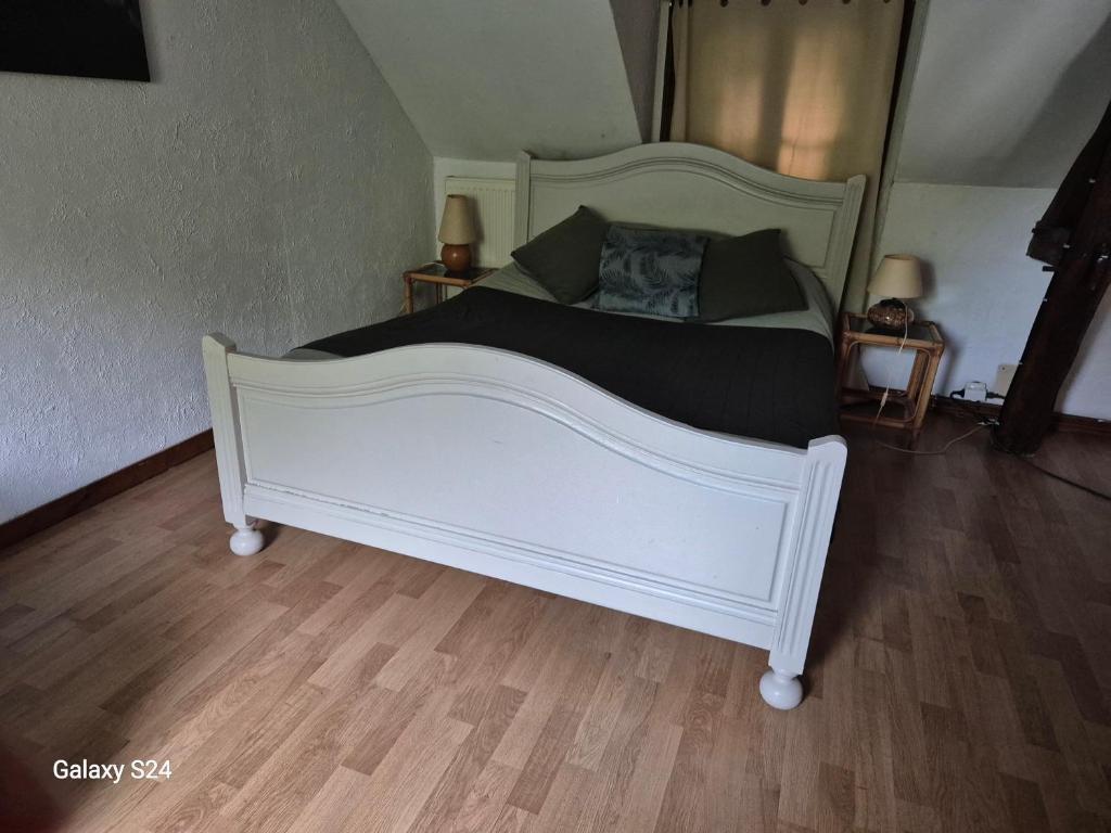 a large white bed in a room with wooden floors at Ancienne étable in Pierrefitte-sur-Sauldre