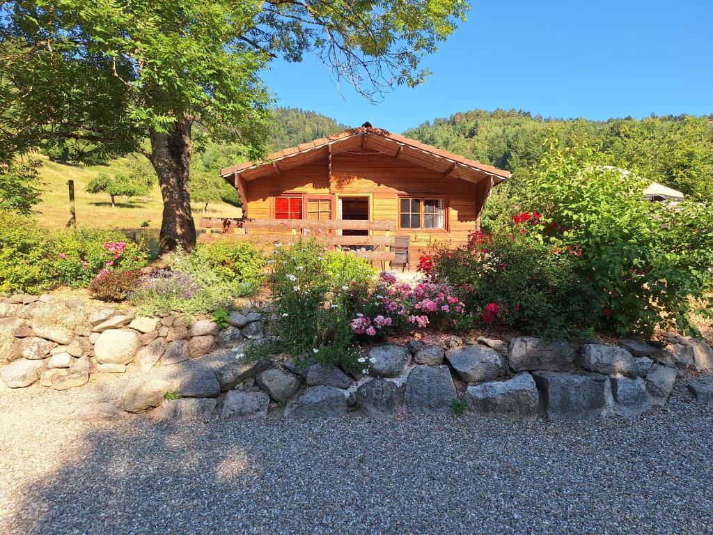 a log cabin with flowers in front of it at Le Repaire de Mitzerlé in Mitzach
