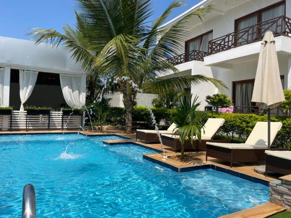 a swimming pool with chairs and a hotel at Minah bungalows in Nungwi