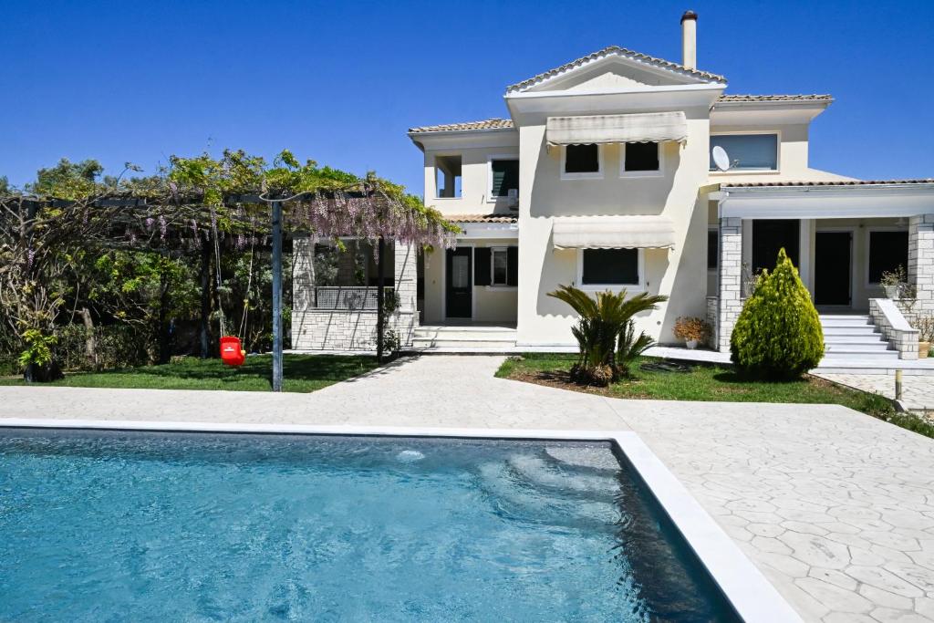 a white house with a swimming pool in front of it at Violet Luxury Villa in Lefkada