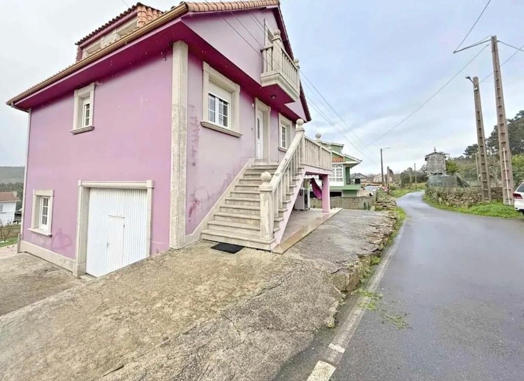 a pink house with stairs on the side of a street at Casa Mar de Neaño in Neaño