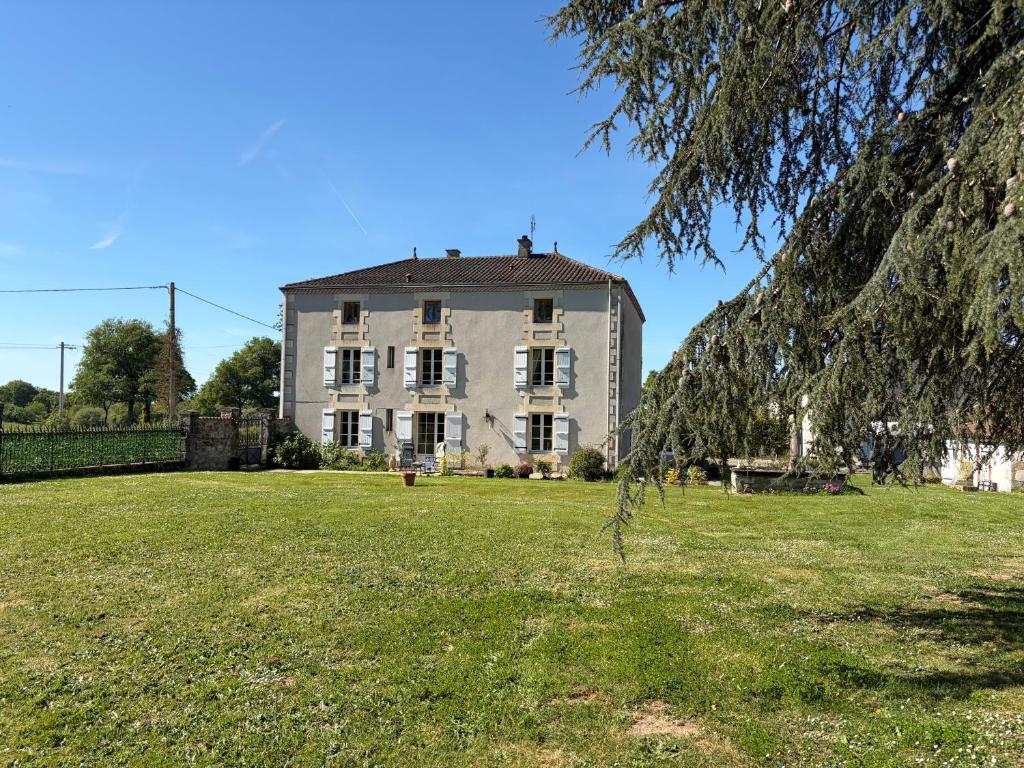 a large white building in a field with a tree at Chez Paulet A welcome break for peace and tranquility - route C27 in Lobard