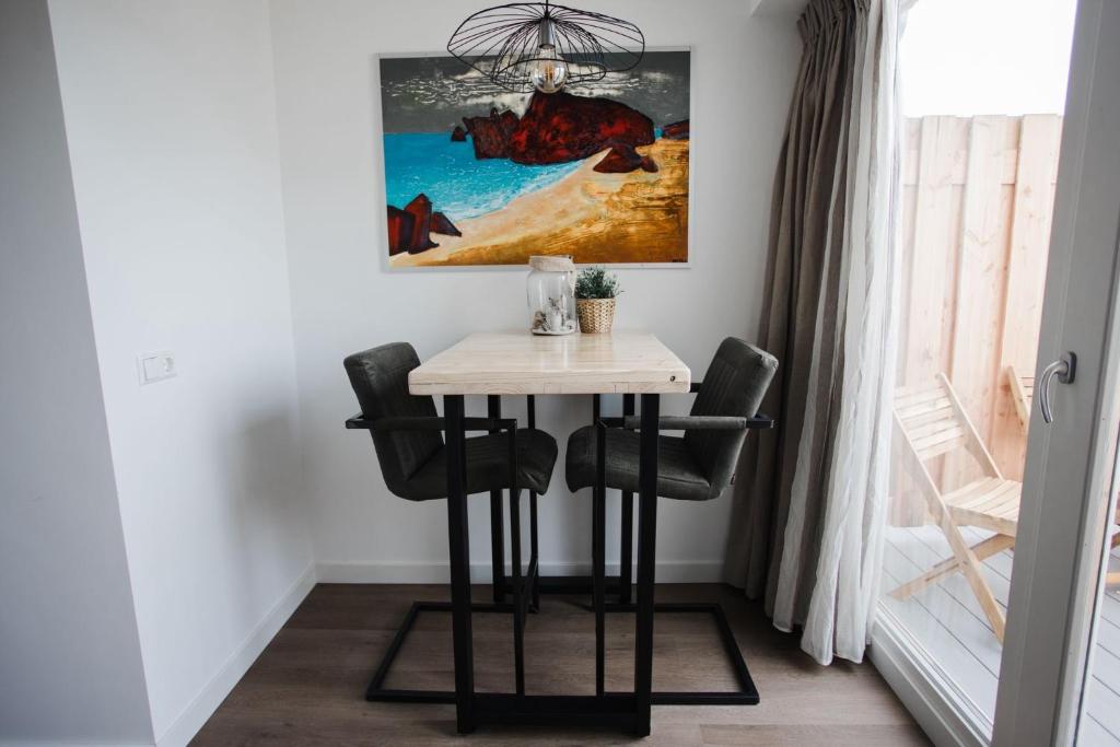 a small table in a room with a painting on the wall at vredehof appartement in Sint Maartensbrug