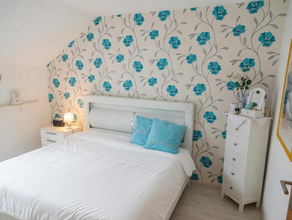 a bedroom with a white bed and blue flowers on the wall at Dreiflüsse Appartement - Traumgarten mit Grill und Pavillon, WLAN, Küche und Parkplatz in Salzweg
