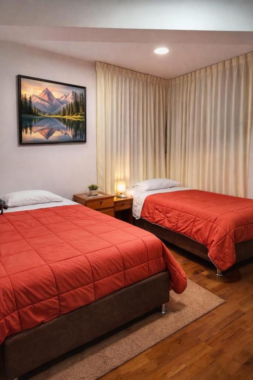 two beds in a hotel room with red covers at Amatista Apartment in Cusco