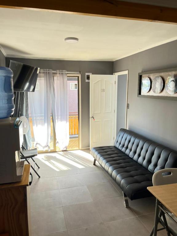 a living room with a black leather couch in a room at Hostal JVDepartamento B in Nogales