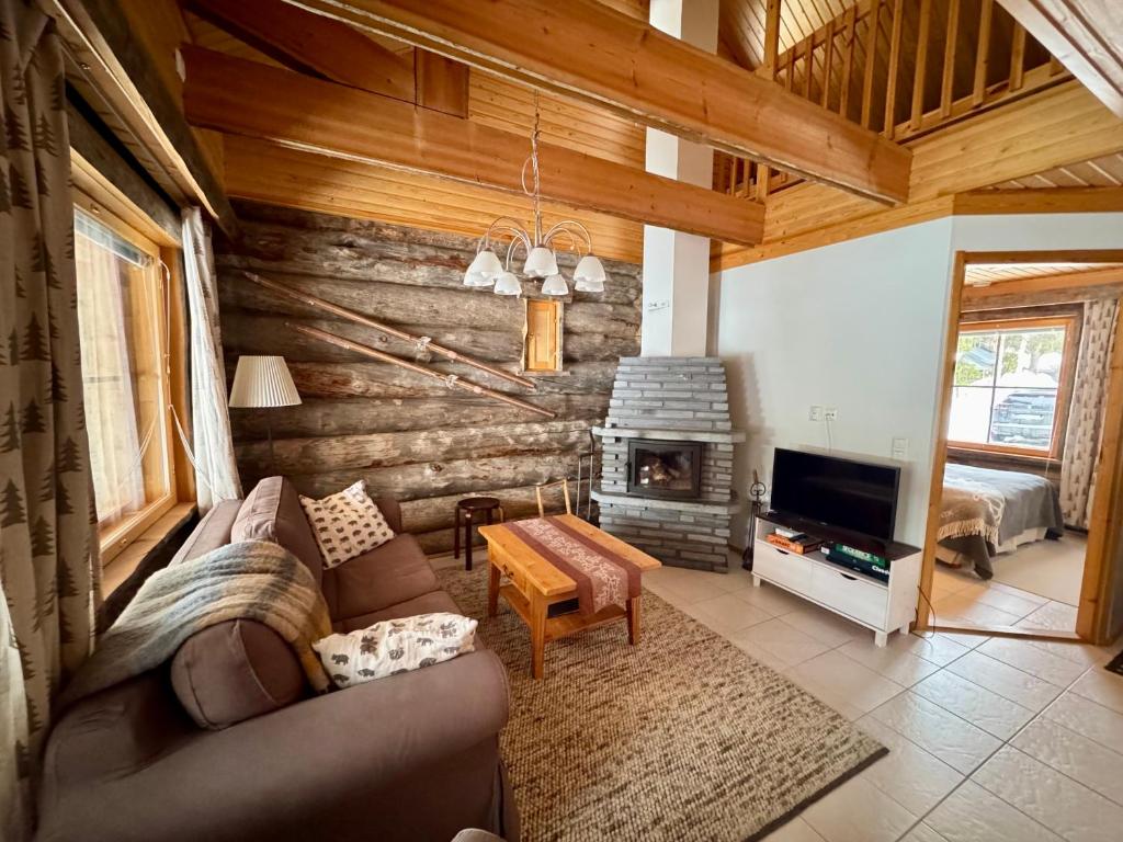 a living room with a couch and a fireplace at Usva Cabins Ylläs - Sapara J 38 in Äkäslompolo