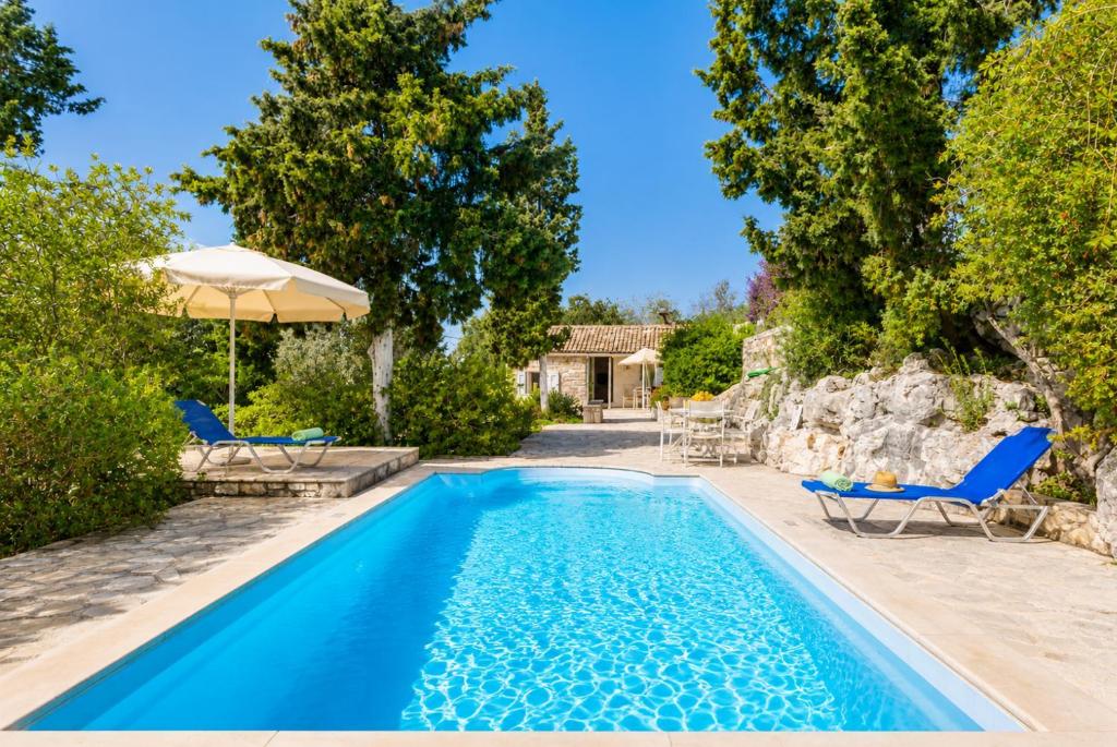 a swimming pool with two chairs and an umbrella at Millers Cottage Large Private Pool AC WiFi in Vlachopoulátika
