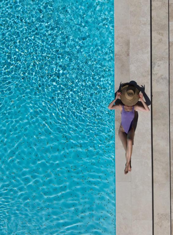 a woman in a hat sitting on the edge of a swimming pool at Maison C in Nice