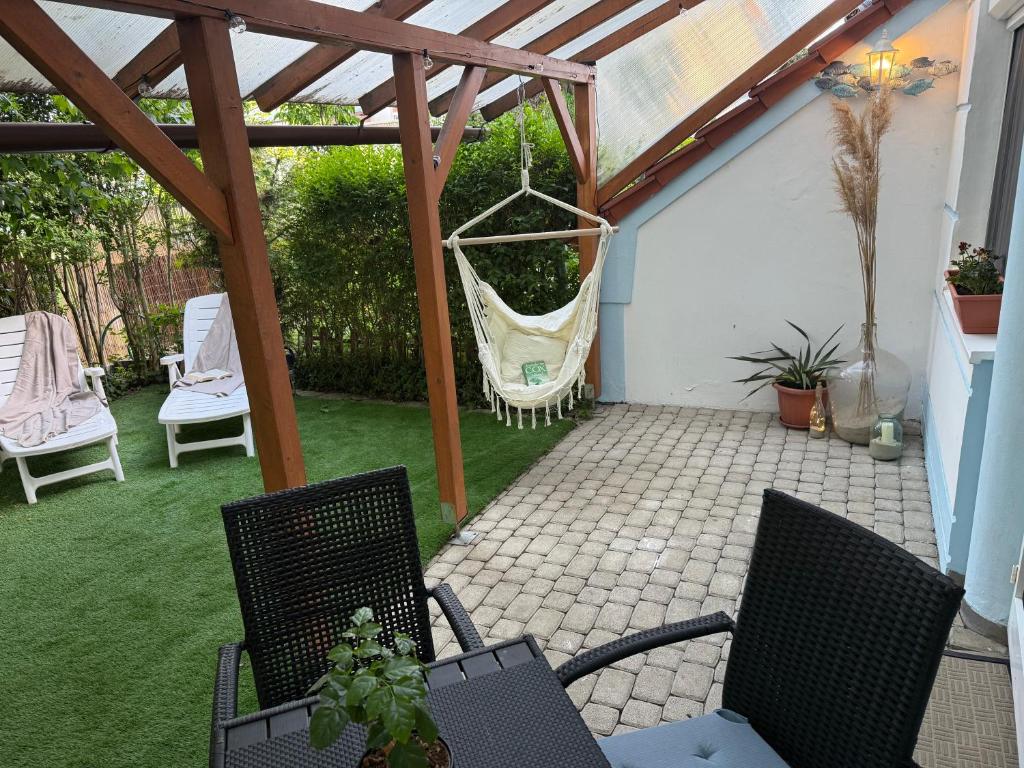 a patio with a hammock hanging from a pergola at Thermal Oazis Apartman in Mosonmagyaróvár