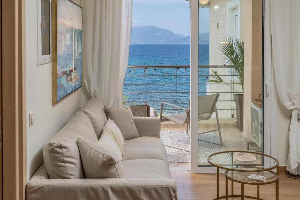 a living room with a couch and a view of the ocean at Aura Seaside Apartment in Karavomylos
