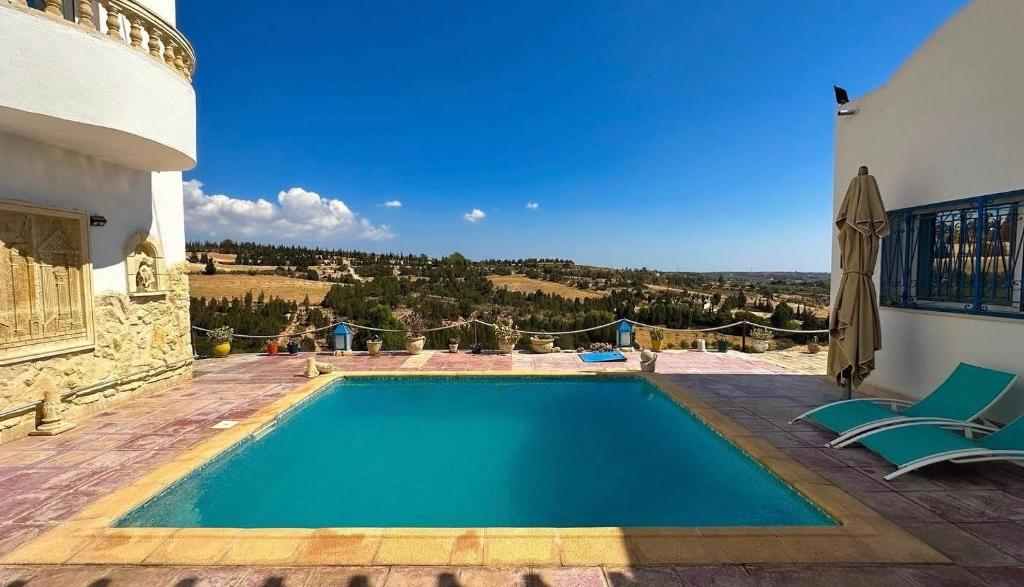 a swimming pool with two chairs and a house at Dar Kmaar in Hammamet