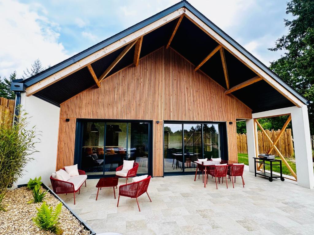 a pavilion with red chairs and tables on a patio at L'Instant Cottage, Chic et Spa près d'Amboise in Saint-Règle
